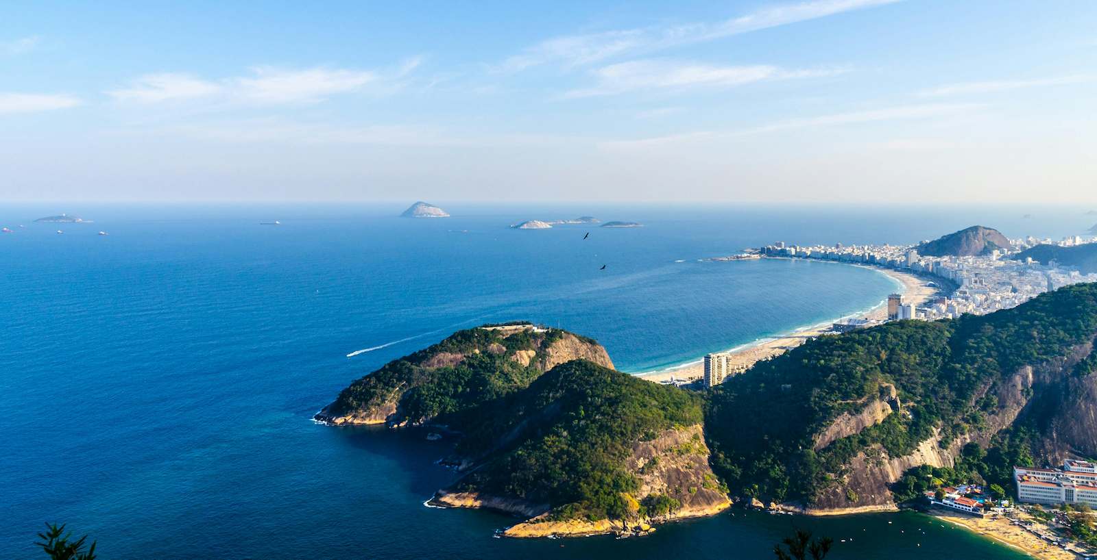 arial angle of Rio de Janeiro, Brazil birds fly over the city on the coast on a calm, sunny day.