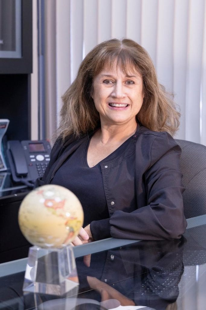 portrait of Orleans travel health nurse Ilona sitting at a desk